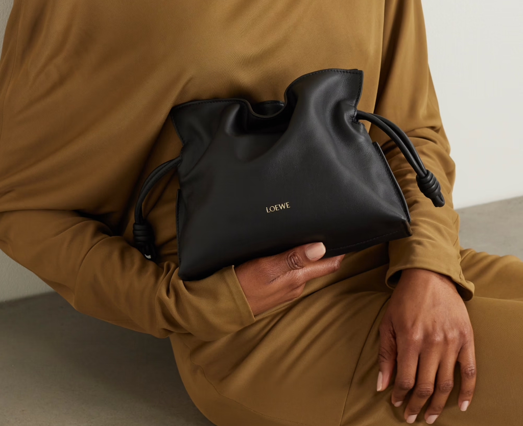 A sleek black leather bucket bag with gold-tone hardware and an adjustable strap, offering a sophisticated look for both casual and formal occasions.